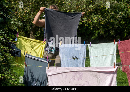 Femme accrochant la lessive sur la ligne de lavage linge séchage blanchisserie extérieure Clothesline Garden femme accrochant la lessive vêtements extérieurs Air frais Banque D'Images