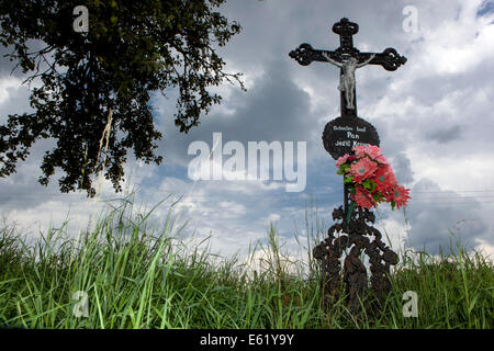 Calvaire avec Jésus et le rouge des fleurs en plastique dans le pays Banque D'Images