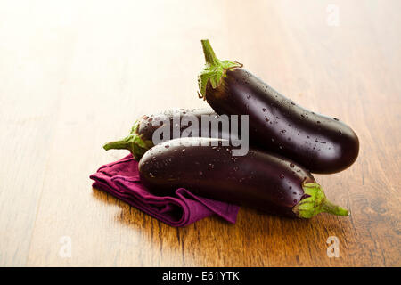 Les aubergines de matières premières ou d'aubergines sur le fond en bois. Banque D'Images