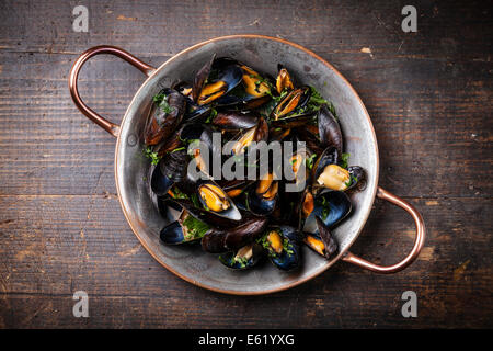 Les moules cuites dans un plat de cuisson en cuivre foncé sur fond de bois Banque D'Images