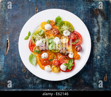 Salade de tomates avec de la mozzarella colorés sur fond de bois bleu Banque D'Images