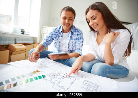 Portrait de jeune couple assis dans leur nouvel appartement et à discuter de son plan Banque D'Images