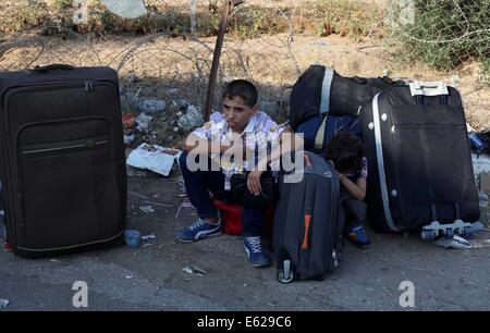 Rafah, bande de Gaza, territoire palestinien. 12e Août, 2014. Les Palestiniens, dans l'espoir de se rendre en Égypte, comme l'attente au point de passage de Rafah entre l'Egypte et le sud de la bande de Gaza, le 12 août 2014. Sous le président égyptien Abdel Fattah al-Sisi, Le Caire a obtenu des fermetures de la frontière de Gaza, l'augmentation de la pression économique sur le Hamas d'un blocus israélien. Parle de mettre fin à un mois de guerre entre Israël et les militants islamistes de Gaza ont fait aucun progrès jusqu'à présent, un responsable israélien a déclaré mardi, ainsi qu'un cessez-le-feu de 72 heures dans l'enclave palestinienne qui s'est tenue, pour la deuxième journée (crédit I Banque D'Images