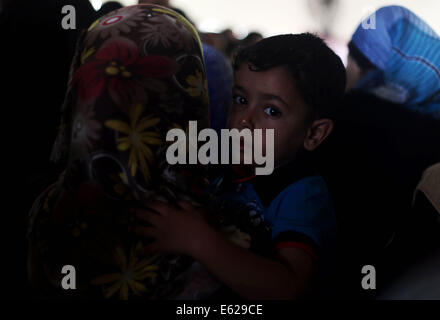 Rafah, bande de Gaza, territoire palestinien. 12e Août, 2014. Un garçon palestinien, dans l'espoir de pénétrer en Egypte avec sa famille, est tenu par sa mère pendant qu'ils attendent au point de passage de Rafah entre l'Egypte et le sud de la bande de Gaza, le 12 août 2014. Sous le président égyptien Abdel Fattah al-Sisi, Le Caire a obtenu des fermetures de la frontière de Gaza, l'augmentation de la pression économique sur le Hamas d'un blocus israélien. Parle de mettre fin à un mois de guerre entre Israël et les militants islamistes de Gaza ont fait aucun progrès jusqu'à présent, un responsable israélien a déclaré mardi, ainsi qu'un cessez-le-feu de 72 heures dans le shattered Palestini Banque D'Images