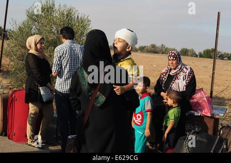 Rafah, bande de Gaza, territoire palestinien. 12e Août, 2014. Un garçon palestinien, dans l'espoir de pénétrer en Egypte avec sa famille, est tenu par sa mère pendant qu'ils attendent au point de passage de Rafah entre l'Egypte et le sud de la bande de Gaza, le 12 août 2014. Sous le président égyptien Abdel Fattah al-Sisi, Le Caire a obtenu des fermetures de la frontière de Gaza, l'augmentation de la pression économique sur le Hamas d'un blocus israélien. Parle de mettre fin à un mois de guerre entre Israël et les militants islamistes de Gaza ont fait aucun progrès jusqu'à présent, un responsable israélien a déclaré mardi, ainsi qu'un cessez-le-feu de 72 heures dans le shattered Palestini Banque D'Images