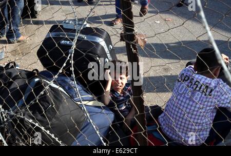 Rafah, bande de Gaza, territoire palestinien. 12e Août, 2014. Un garçon palestinien, dans l'espoir de pénétrer en Egypte avec sa famille, est assis sur des valises qu'il attend au point de passage de Rafah entre l'Egypte et le sud de la bande de Gaza, le 12 août 2014. Sous le président égyptien Abdel Fattah al-Sisi, Le Caire a obtenu des fermetures de la frontière de Gaza, l'augmentation de la pression économique sur le Hamas d'un blocus israélien. Parle de mettre fin à un mois de guerre entre Israël et les militants islamistes de Gaza ont fait aucun progrès jusqu'à présent, un responsable israélien a déclaré mardi, ainsi qu'un cessez-le-feu de 72 heures dans la salle palestinienne brisée Banque D'Images