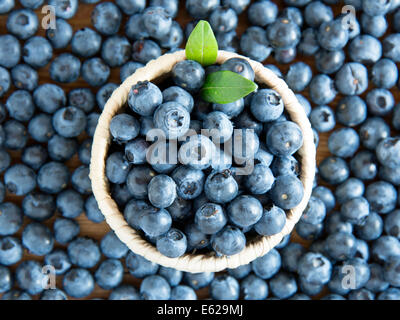 Bleuets frais dans le bol d'osier sur fond de bois rustique Banque D'Images