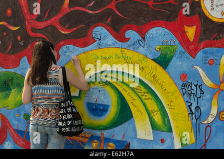 Une photographie d'une jeune fille s'appuyant sur l'ancien mur de Berlin à l'East Side Gallery à Berlin. Banque D'Images