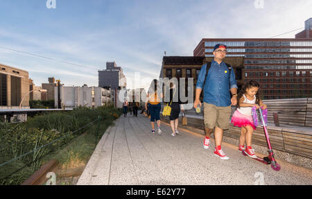 Une jeune fille monte un scooter près de son père à la ligne élevée à New York, une voie surélevée transformé en parc. Banque D'Images