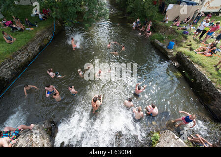 Week-end festivaliers se rafraîchir dans la rivière Bray près de Brayford au Festival somersault, Devon Banque D'Images