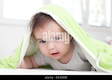 Baby Girl se cache sous la couverture blanche et verte Banque D'Images