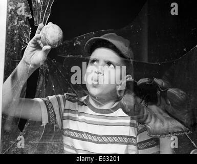 1950 garçon EN TEE-SHIRT ET LA DÉPOSE DE LA FENÊTRE cassée Banque D'Images