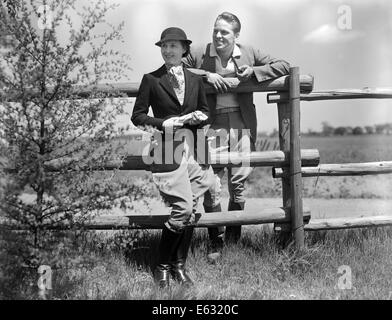 1930 Vêtements d'ÉQUITATION ÉQUITATION COUPLE STANDING TOGETHER PAR RAIL FENCE MAN SMOKING PIPE Banque D'Images