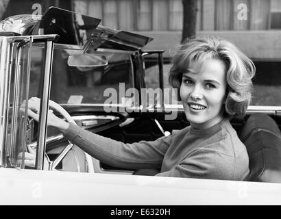 1960 SMILING BLONDE WOMAN DRIVING CONVERTIBLE CAR LOOKING AT CAMERA Banque D'Images