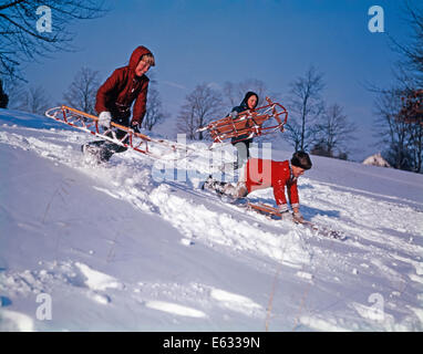 1960 Trois garçons de la luge sur la colline couverte de neige Banque D'Images