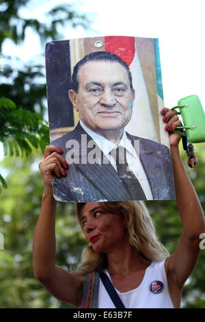 Le Caire, Égypte. 13e Août, 2014. Un partisan de l'ancien président égyptien Hosni Moubarak est titulaire d'un poster de lui en dehors de l'Hôpital Militaire de Maadi au Caire, Égypte, le 13 août 2014. L'ancien président égyptien Hosni Moubarak a déclaré mercredi dans la cour qu'il n'a pas donné l'ordre de tuer des manifestants au cours de la 2011 soulèvement populaire contre son long-temps, la règle des Nile TV signalés. Credit : Ahmed Gomaa/Xinhua/Alamy Live News Banque D'Images