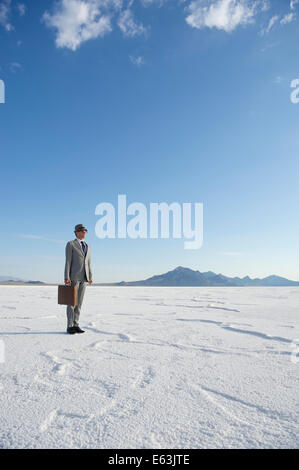 Voyageant businessman standing outdoors prêt avec porte-documents à la recherche sur l'horizon désertique spectaculaire Banque D'Images