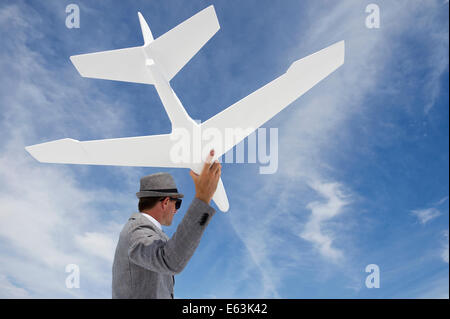 Homme d'entrepreneur battant modèle d'avion blanc contre le ciel bleu Banque D'Images