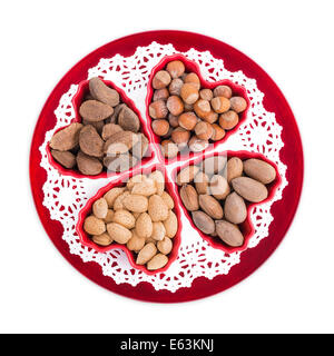 Groupe d'écrous la santé cardiaque, y compris les amandes, noisettes, noix de pécan, noix du Brésil et affichées dans des bols en forme de coeur sur une plaque rouge Banque D'Images