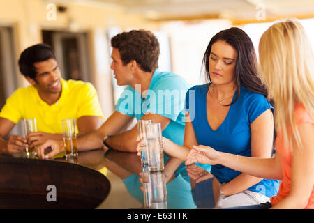 Triste fille assise au bar avec des amis Banque D'Images