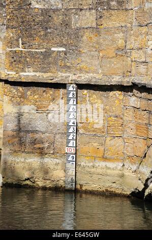 Cité médiévale pont de pierre sur la rivière Windrush montrant le marqueur de profondeur, Burford, Oxfordshire, Angleterre, Royaume-Uni, Europe de l'Ouest. Banque D'Images