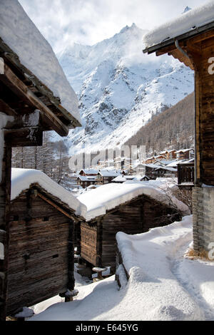 Vue sur le village de Saas-Fee alpin suisse en hiver, avec ses maisons en bois avec toit couvert de neige. Banque D'Images