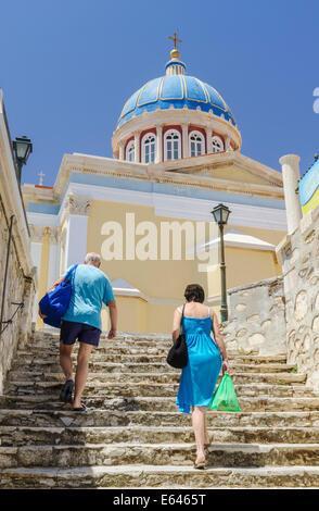 Un couple à pied jusqu'à l'église de Saint dôme bleu Nikolas, Ermoupoli, l'île de Syros, Cyclades, Grèce Banque D'Images