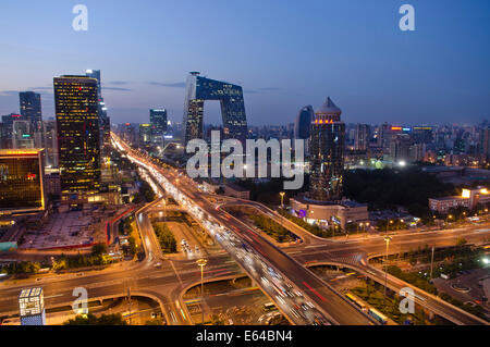 Belle vue panoramique sur la ville de la capitale chinoise et le célèbre monument du siège de CCTV, avec les lumières de la circulation sur le troisième périphérique et les bureaux et les bâtiments éclairant la scène en début de soirée. Rare scène panoramique pendant l'heure bleue juste après le coucher du soleil avec un ciel clair à Guomao, le quartier central des affaires de Beijing, situé dans le quartier de Chaoyang, Chine, RPC. © Olli Geibel Banque D'Images