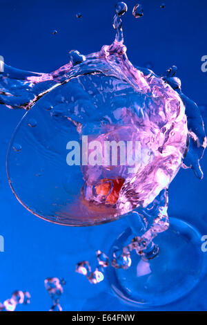 Cocktail dans le verre avec des touches close-up sur fond bleu Banque D'Images