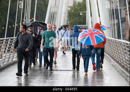 Golden Jubilee Bridge, Londres, Royaume-Uni. 14 août 2014. Les précipitations a frappé Londres aujourd'hui que le Met Office a émis des avertissements de temps violent et l'Agence de l'environnement mettre 19 alertes inondations dans tout le pays, dont 8 dans le sud-est. Sur la photo : les navetteurs et les touristes à pied à travers le Golden Jubilee Bridge à Londres comme la capitale est touchée par de fortes pluies. Credit : Lee Thomas/Alamy Live News Banque D'Images