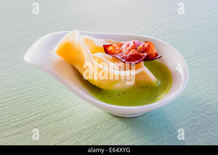 Les pâtes maison vrac remplis de fromage mascarpone et le Parmesan, le zeste de citron servi avec des petits pois, purée de petits pois et chips. Banque D'Images