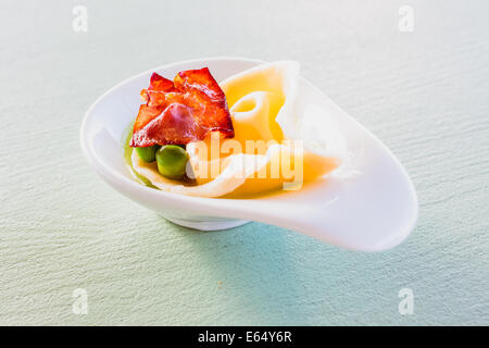 Les pâtes maison vrac remplis de fromage mascarpone et le Parmesan, le zeste de citron servi avec des petits pois, purée de petits pois et chips. Banque D'Images