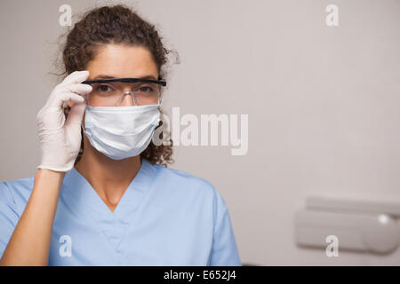 Dentiste dans un masque chirurgical et des lunettes de protection Banque D'Images