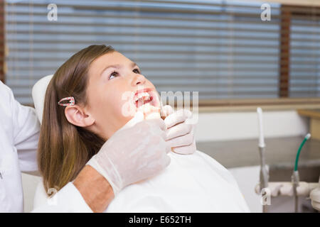 Dentiste mettant l'enrouleur sur la bouche petite fille Banque D'Images