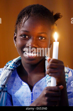 Fille (11 ans) maintenant la bougie dans une église catholique à Kaolack, Sénégal, Afrique Banque D'Images