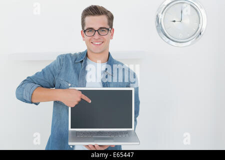 Nerdy man holding laptop smiling at camera Banque D'Images