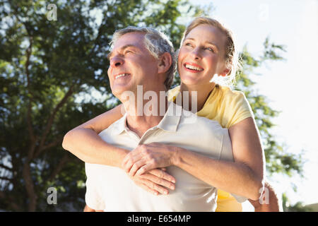 Happy senior man giving son partenaire un piggy back Banque D'Images