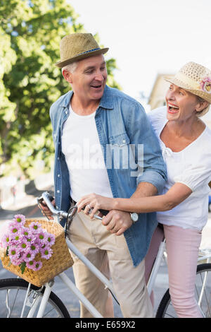 Happy mature couple going pour une balade à vélo dans la ville Banque D'Images