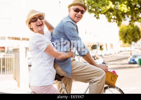 Happy mature couple going pour une balade à vélo dans la ville Banque D'Images