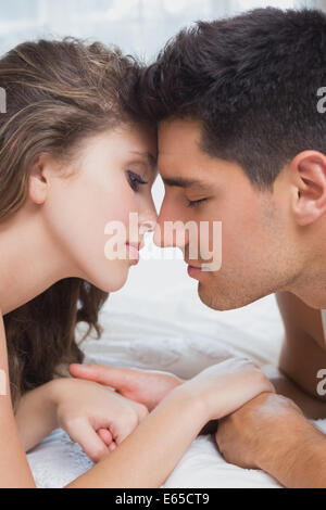 Vue latérale du couple romantique au lit à la maison Banque D'Images
