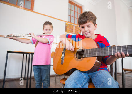 Cute pupils jouant la flûte et guitare en classe Banque D'Images