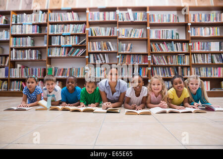 Élèves et professeur mignon lying on floor in library Banque D'Images