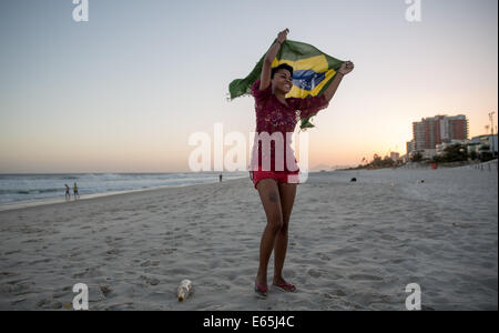 Rio de Janeiro, Brésil. 7e août, 2014. Une jeune femme tient le drapeau brésilien dans sa main tandis qu'elle pose sur la plage de Barra à Rio de Janeiro, Brésil, 7 août 2014. Les Jeux olympiques d'été de 2016 vont être menées à Rio de Janeiro. Photo : Michael Kappeler/dpa/Alamy Live News Banque D'Images
