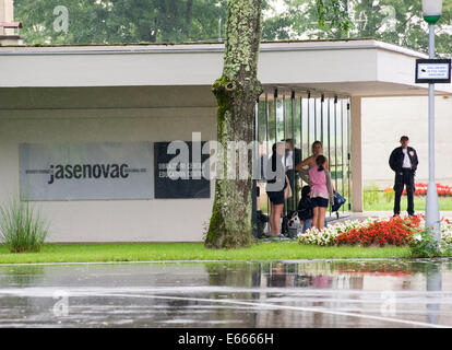 Jasenovac, Croatie. 6e août, 2014. Les gens se cacher de la pluie à l'entrée du Musée Mémorial de Jasenovac Jasenovac, la Croatie, le 6 août 2014. Le site du mémorial de Jasenovac Memorial Museum a été ouvert en 1968 à proximité du site original de l'ancien camp de concentration d'Oustachi. D'innombrables juifs, tziganes, Serbes, Croates, et d'autres ont perdu leur vie dans le tristement célèbre camp de la mort de 1941 à 1945. © Lisanin Miso/Xinhua/Alamy Live News Banque D'Images