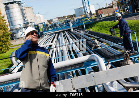 Travailleurs du pétrole et du gaz avec le géant à la raffinerie pipelines Banque D'Images