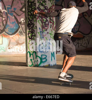 Un jeune homme la planche à roulettes dans un salon avec graffiti Banque D'Images