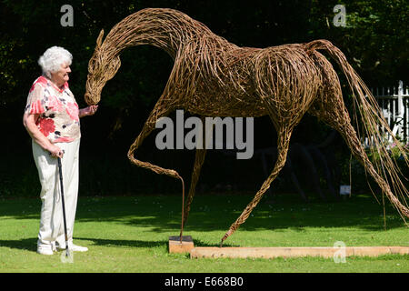 Femme prétendant pour nourrir un cheval willow par le sculpteur Sophie Courtiour dans le domaine de Saumarez Hall, St Martins, Guernsey, Channel Islands, GB Banque D'Images