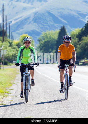 Homme d'âge moyen & woman riding bikes on country road Banque D'Images