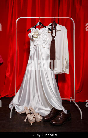 Robe de mariée blanche accroché à l'armoire à côté de l'époux chemise et cravate Banque D'Images