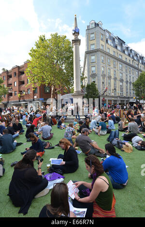 Seven Dials, Londres, Royaume-Uni. 16 août 2014. Les sept cadrans est libre du trafic et le couvercle dans le gazon artificiel que les gens apprécient le festival. Crédit : Matthieu Chattle/Alamy Live News Banque D'Images